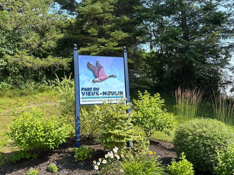 Panneau d'entrée du Parc du Vieux-Moulin, entouré de vivaces en fleurs